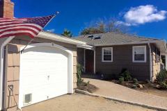 Professional painters in Suffolk County New York stain an exterior of a home tan with black shutters and white trim