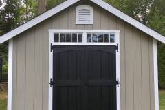 Outside shed painted tan with white trim and black doors by Long Island Painter